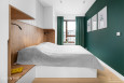 Sypialnia z dużym łóżkiem kontynentalnym i zielonymi ścianami