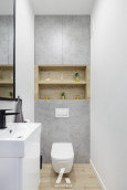 Łazienka z imitacją betonowych płytek oraz białą muszlą