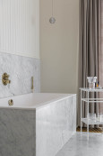 Łazienka z prostokątną wanną w zabudowie ze złota armaturą łazienkową