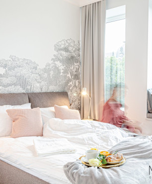 Sypialnia z szarym, tapicerowanym łóżkiem kontynentalnym