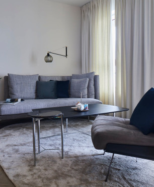 Salon z szarą sofą i wygodnym fotelem na metalowych nogach