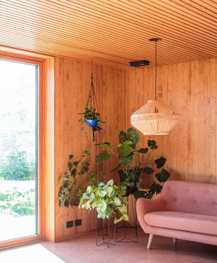 Salon z drewnianą boazerią na ścianie oraz z modną lampą ażurową, wiszącą