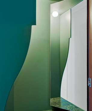 Wejście do mieszkania z zielonymi ścianami i dużym lustrem