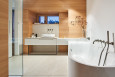 Duża łazienka z wanną w zabudowie z drewnianymi elementami na ścianie