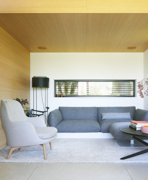 Salon z szarą sofą oraz z drewnem na ścianie i suficie