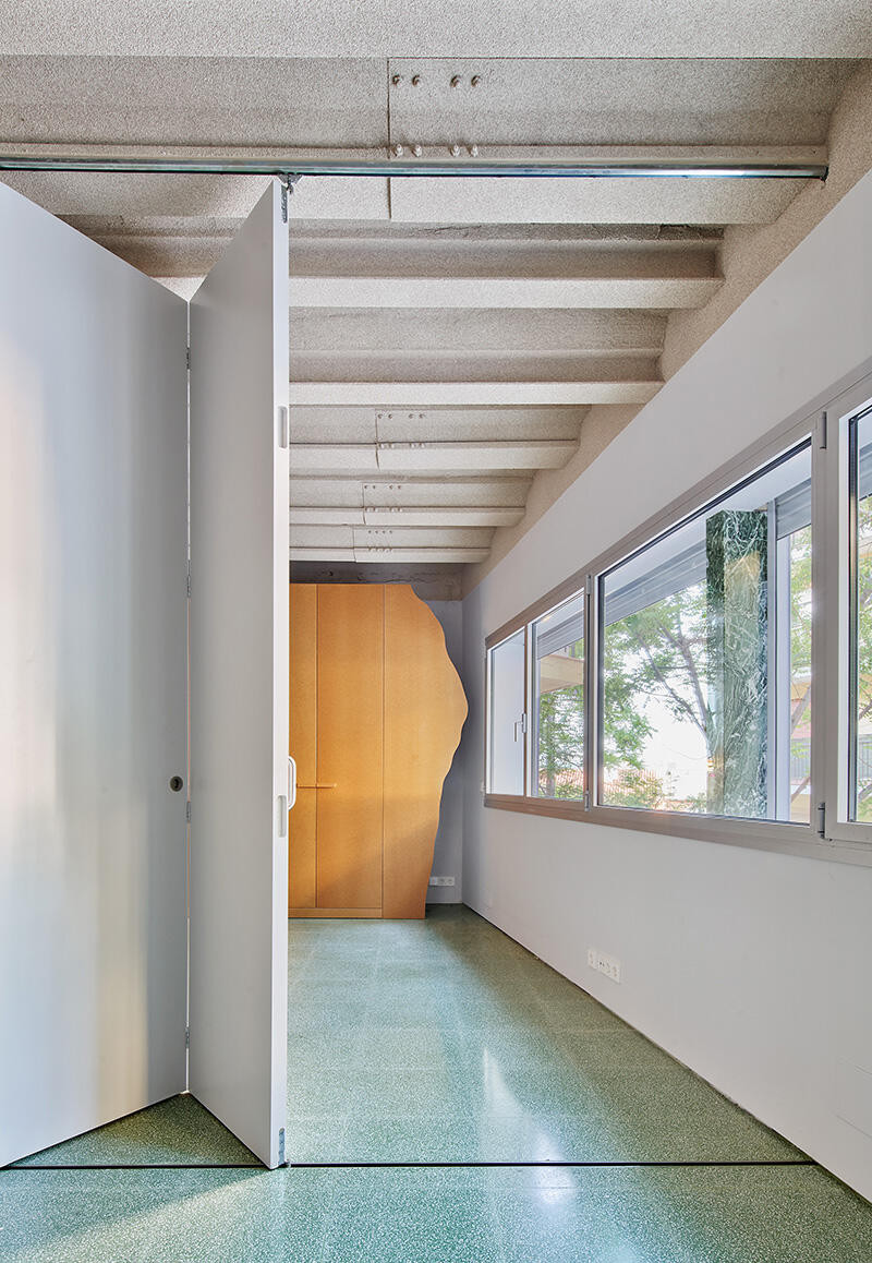 Wąski korytarz z betonowym sufitem oraz z zielonymi płytkami na podłodze