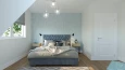 Sypialnia z szarym, tapicerowanym łóżkiem kontynentalnym oraz turkusową tapetą na ścianie