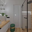 Łazienka z prysznicem i białą szafką wiszącą z drewnianym blatem