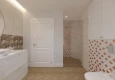 Łazienka z prysznicem, białą szafką wiszącą oraz lustrem okrągłym