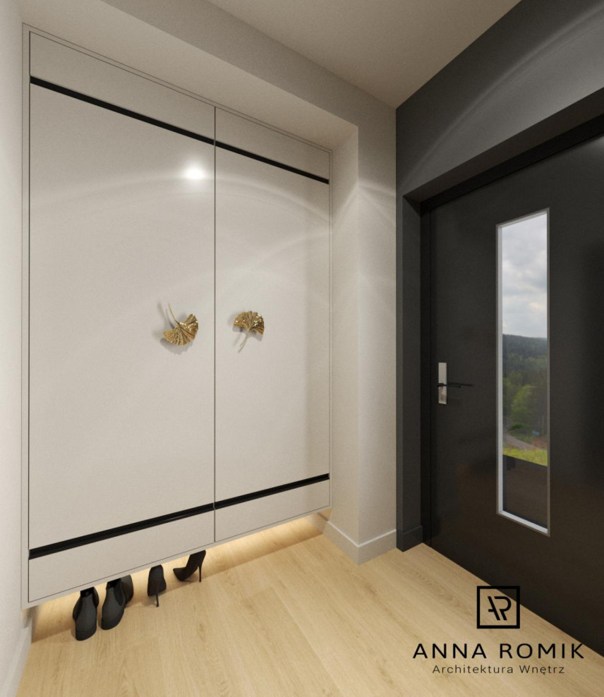 Projekt wejścia do mieszkania z dużą białą szafą ze złotymi klamkami
