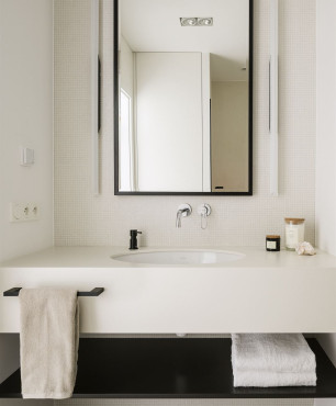 Projekt łazienki z białymi płytkami na ścianie oraz prostokątnym lustrem w czarnej ramie