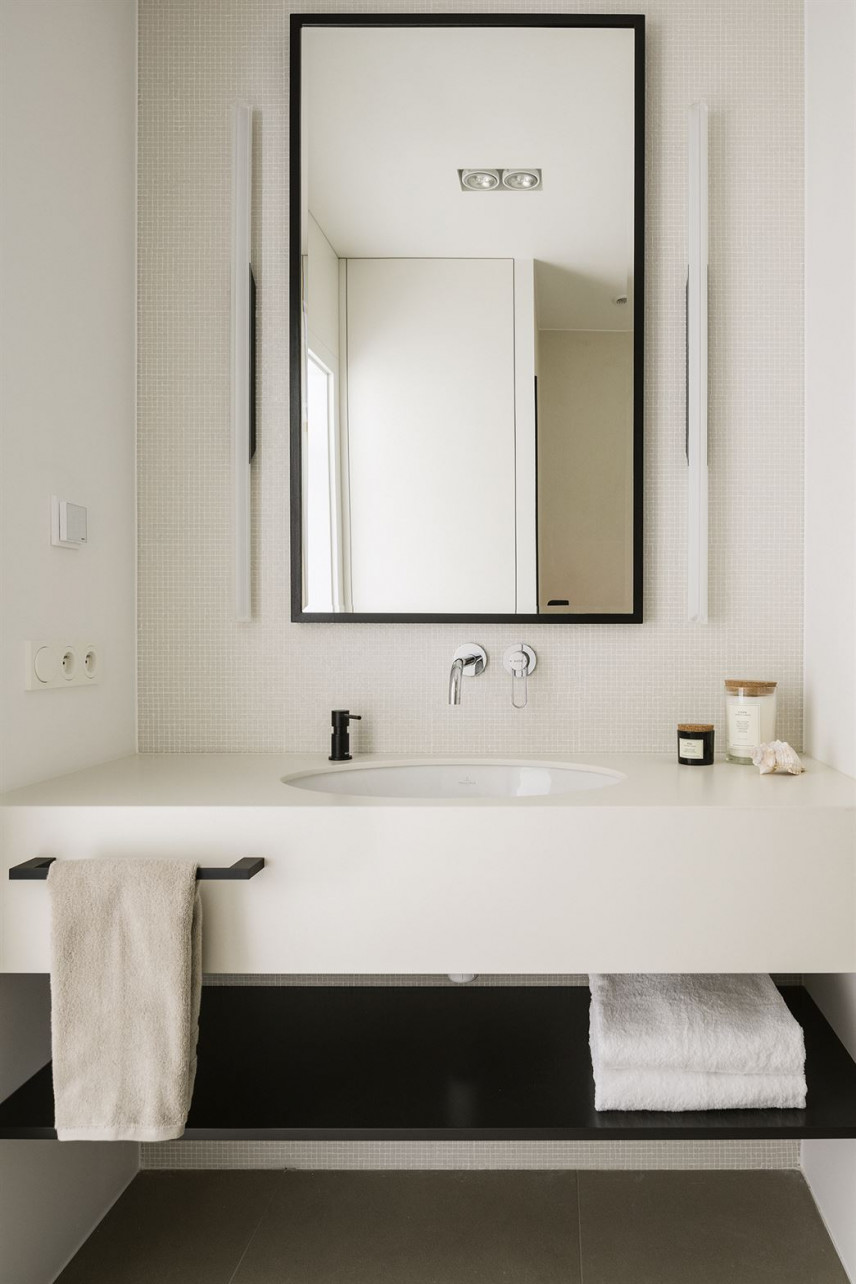 Projekt łazienki z białymi płytkami na ścianie oraz prostokątnym lustrem w czarnej ramie
