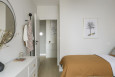 Projekt sypialni z łóżkiem kontynentalnym, białą komoda oraz lustrem w czarnej ramie