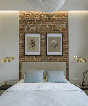 Sypialnia ze złotymi kinkietami oraz cegłą na ścianie