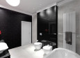 Projekt łazienki z białymi płytkami na podłodze i czarnymi na ścianie