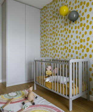 Przytulny pokój dziecięcy z łóżeczkiem dla noworodka oraz białą szafą