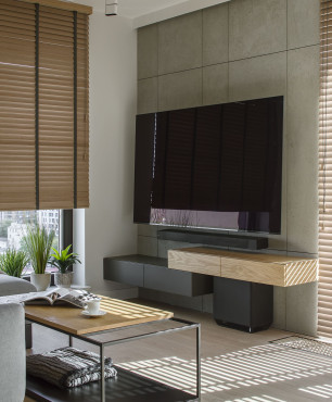 Salon z drewnianymi żaluzjami oraz telewizorem na ścianie