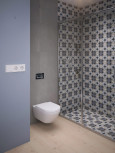 Łazienka z szaro-niebieską ścianą oraz z prysznicem z wzorzystym wzorem skandynawskim na płytkach