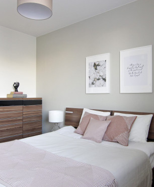 Sypialnia z drewnianym łóżkiem kontynentalnym oraz komodą stojącą z drewnianym blatem
