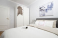Sypialnia z szarym łóżkiem kontynentalnym oraz białą szafą z drzwiami wahadłowymi