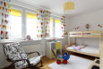 Pokój dziecięcy z piętrowym, drewnianym łóżkiem oraz z kolorowymi zasłonami