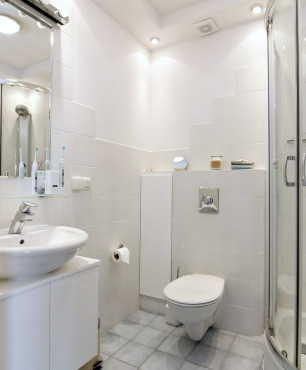 Łazienka z prysznicem narożnym oraz białym zlewem stojącym na białej szafce