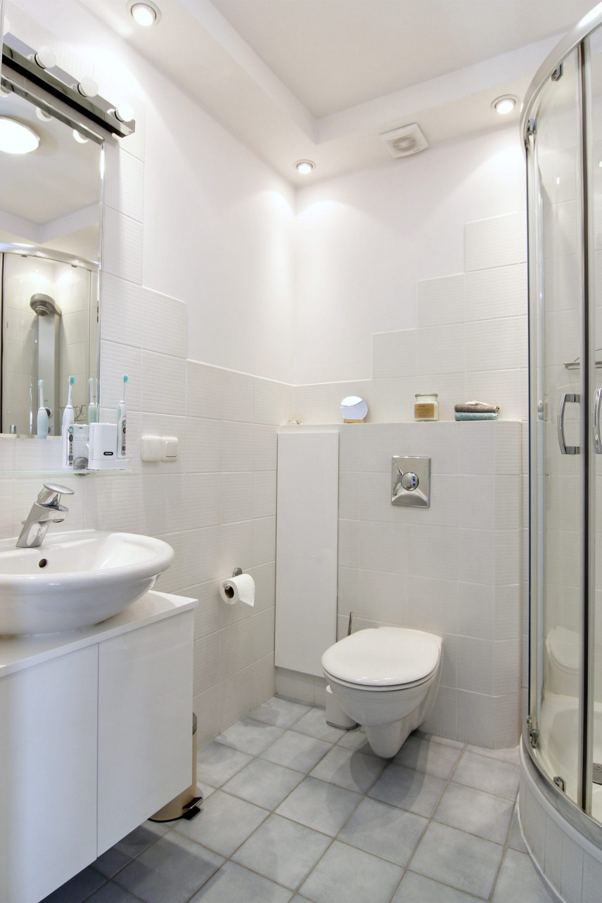 Łazienka z prysznicem narożnym oraz białym zlewem stojącym na białej szafce