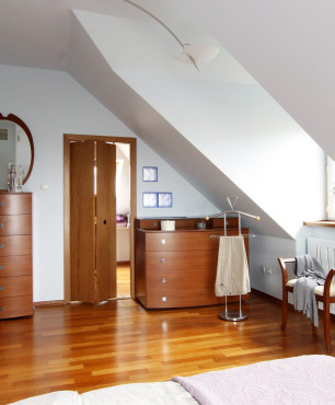 Sypialnia na poddaszu z klasycznymi meblami z frontem w kolorze orzechowym