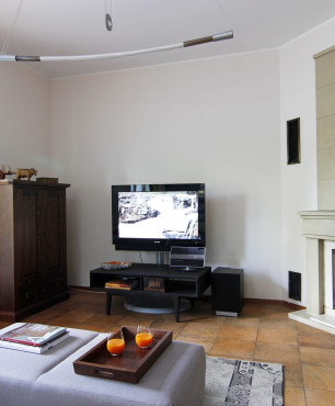 Salon z telewizorem montowanym do stojącego stojaka oraz z kominkiem