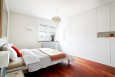 Sypialnia z białą zabudową meblową oraz z panelami w kolorze wenge