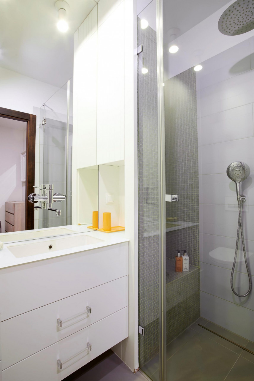 Mała łazienka z białą szafką stojącą z szufladami oraz ze zlewem podblatowym i prysznicem