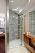 Oryginalna łazienka z prysznicem z brodzikiem oraz jedną ścianą z grubego szkła
