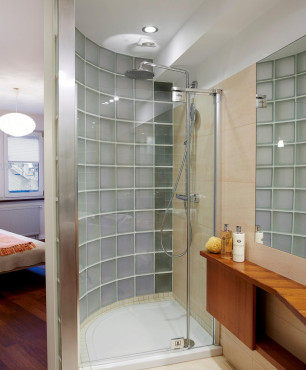 Oryginalna łazienka z prysznicem z brodzikiem oraz jedną ścianą z grubego szkła