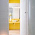 Łazienka z żółtymi płytkami na ścianie oraz z panelami na podłodze