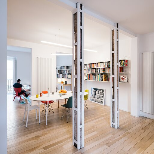 Jadalnia połączona z biurem domowym oraz z półkami montowanymi do ściany z dużą ilością książek