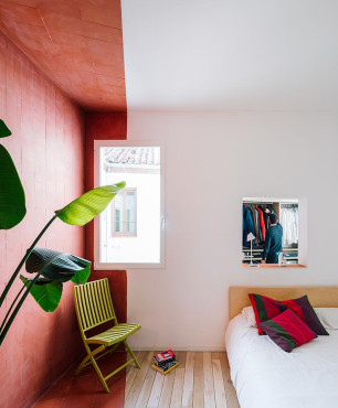 Sypialnia z drewnianym łóżkiem kontynentalnym oraz z jedną czerwoną ścianą