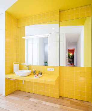 Łazienka z dużym lustrem nad blatem oraz z żółtymi kafelkami na ścianie