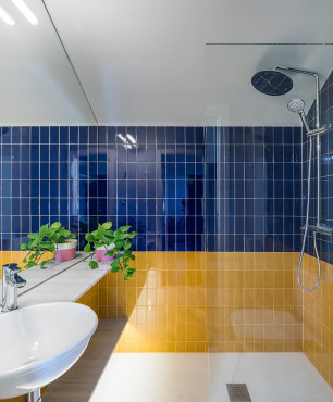 Łazienka z prysznicem oraz niebiesko-żółtymi płytkami na ścianie