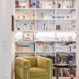 Biblioteczka w salonie montowana na całą ścianę z wygodnym fotelem