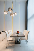 Wysoka jadalnia z dużym stołem i z wyjątkowymi lampami wiszącymi ze szklanymi kloszami
