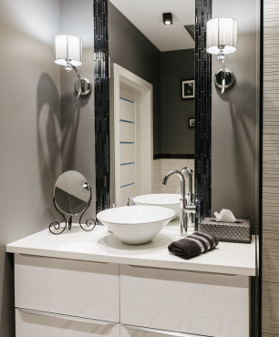 Łazienka z szarym kolorem ścian oraz z kinkietami w stylu glamour montowanymi przy lustrze