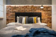 Sypialnia z cegłą na ścianie oraz z czarnym łóżkiem kontynentalnym
