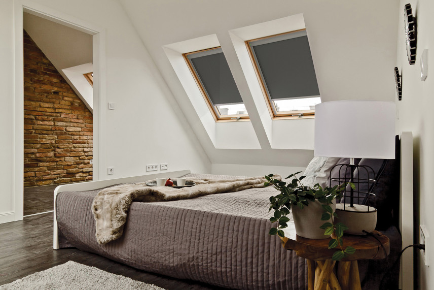 Sypialnia na poddaszu z cegłą na ścianie oraz z oknami dachowymi