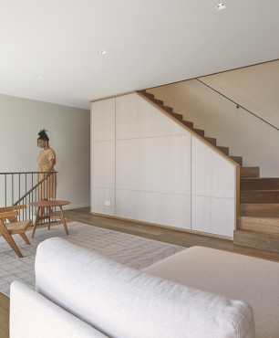 Salon z jasnym drewnem na ścianie oraz z jednobiegowymi schodami