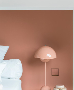 Sypialnia z brązowym kolorem ścian oraz stylową lampką stojącą
