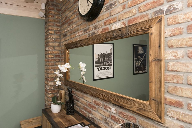 Rustykalny salon z dużym, prostokątnym lustrem zamontowanym na ścianie z cegły