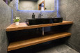 Nowoczesna łazienka z czarnym zlewem nablatowym oraz szarymi płytkami na ścianie i podłodze