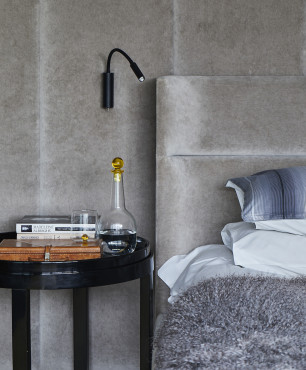 Sypialnia z tapicerowanym łóżkiem oraz stolikiem nocnym w kolorze czarnym