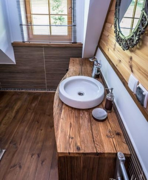 Łazienka na poddaszu z drewnianą szafką oraz z drewnianymi elementami na ścianie