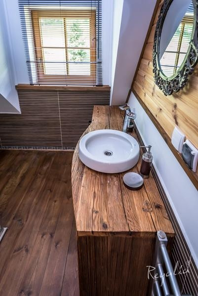 Łazienka na poddaszu z drewnianą szafką oraz z drewnianymi elementami na ścianie
